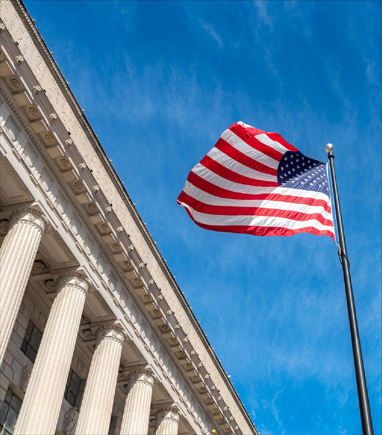 American flag flying beside a columned government building.